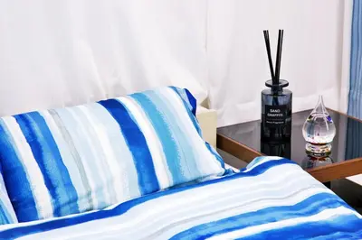 a bed with a blue and white pillow and a vase at Aries Nishi-Shinjuku 302 in Tokyo