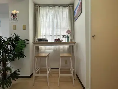 a small kitchen with two stools and a window at nestay apartment tokyo itabashi in Tokyo