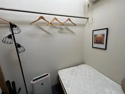 a room with a white wall with hangers on the wall at Backpackers' asakusa share house 