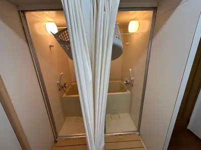 a shower with a curtain in a bathroom at Backpackers' asakusa share house 