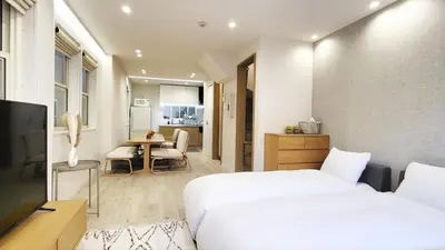 a bedroom with a bed and a table and a kitchen at Hotel STAY ARI Higashishinjuku in Tokyo