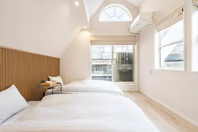 two beds in a room with a window at Hotel STAY ARI Higashishinjuku in Tokyo