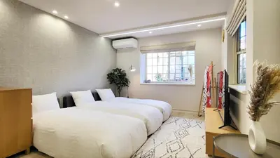 a room with three beds in it with a window at Hotel STAY ARI Higashishinjuku in Tokyo