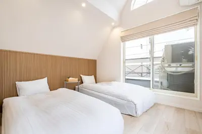 two beds in a room with a window at Hotel STAY ARI Higashishinjuku in Tokyo