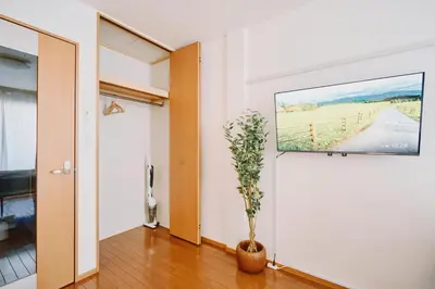 a room with a tv on a wall with a plant at Evergreen Apartment Hotel in Tokyo