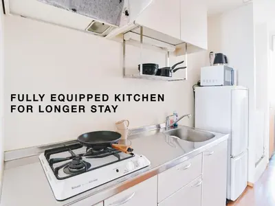 a white kitchen with a stove and a sink at Evergreen Apartment Hotel in Tokyo