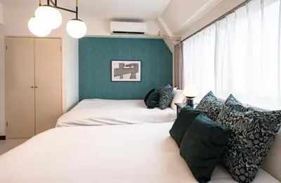 a bedroom with two beds and a green wall at \u30d7\u30ea\u30cd\u30c3\u30c4\u65b0\u5bbf\u30d3\u30eb4\u968e in Tokyo