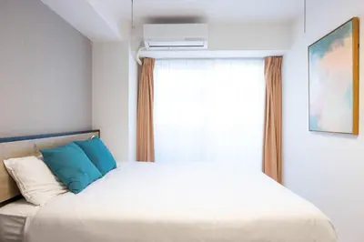 a bedroom with a bed with blue pillows and a window at aLATO\u9326\u7cf8\u753a in Tokyo