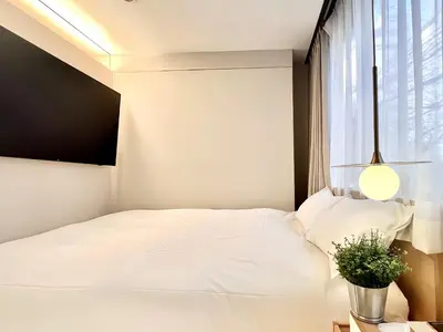 a bedroom with a white bed and a window at \u4e1c\u4eac\u4e0a\u91ce\u8d85\u7ea7\u4e2d\u5fc3 \u8bbe\u8ba1\u5e08\u623f\u95f4Yeoa \u4e0a\u91ce\u516c\u56ed3\u5206\u949f \u8f66\u7ad91\u5206\u949f \u8d85\u7ea7\u7e41\u534e \u514d\u8d39wifi \u6234\u68ee\u5439\u98ce in Tokyo