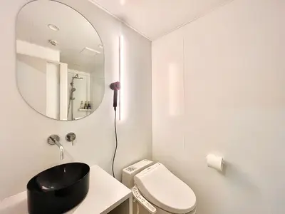 a white bathroom with a mirror and a toilet at \u4e1c\u4eac\u4e0a\u91ce\u8d85\u7ea7\u4e2d\u5fc3 \u8bbe\u8ba1\u5e08\u623f\u95f4Yeoa \u4e0a\u91ce\u516c\u56ed3\u5206\u949f \u8f66\u7ad91\u5206\u949f \u8d85\u7ea7\u7e41\u534e \u514d\u8d39wifi \u6234\u68ee\u5439\u98ce in Tokyo
