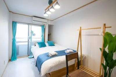 a bedroom with a bed with blue pillows and a window at Rea\u65b0\u5c0f\u5ca92\u4e01\u76ee403 in Tokyo