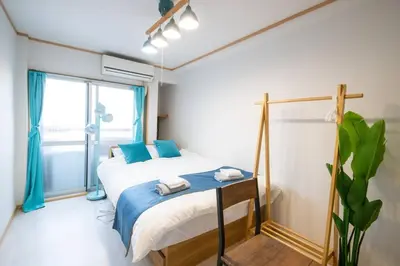 a bedroom with a bed with blue pillows and a window at Rea\u65b0\u5c0f\u5ca92\u4e01\u76ee403 in Tokyo