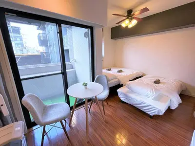two beds in a room with a table and chairs at \u6b4c\u821e\u4f0e\u753a\u306e\u7269\u4ef6 \u6700\u4e0a\u968e \u6771\u65b0\u5bbf\u99c5\u5f92\u6b693\u5206\u65b0\u5bbf\u6e0b\u8c37\u539f\u5bbf\u30a8\u30ea\u30a2 in Tokyo
