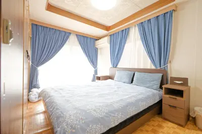 a bedroom with a bed with blue curtains and a window at Tokyo Shinjuku hotel in Tokyo