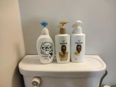 three bottles of cleaning products sitting on the back of a toilet at \u548c\u98a8\u5ba2\u68e7 in Tokyo
