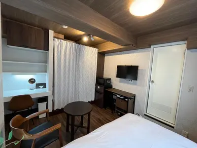 a hotel room with a bed and a table and a tv at Cozy inn Oyama in Tokyo