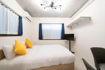 a bedroom with a white bed with yellow pillows at Ferio\u84b2\u7530II in Tokyo