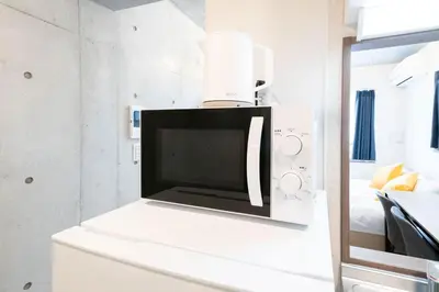 a microwave oven sitting on top of a white cabinet at Ferio\u84b2\u7530II in Tokyo