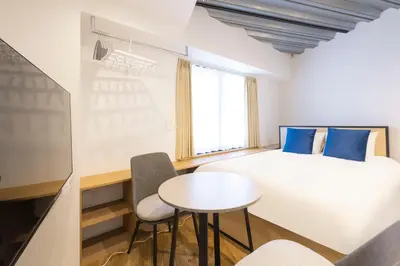 a room with a bed and a table and chairs at Gran Fusion\u6c60\u888b in Tokyo
