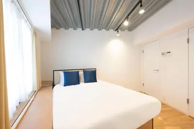 a bedroom with a large white bed with blue pillows at Gran Fusion\u6c60\u888b in Tokyo