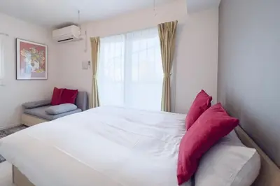 a white bed with red pillows in a bedroom at Livecasa\u4e21\u56fd I in Tokyo