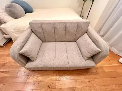 a grey chair sitting on a floor next to a bed at FARE Akihabara - Stylish Spacious Studio 8min from Station 201 in Tokyo