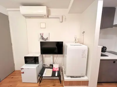 a small kitchen with a microwave and a refrigerator at FARE Akihabara - Stylish Spacious Studio 8min from Station 201 in Tokyo