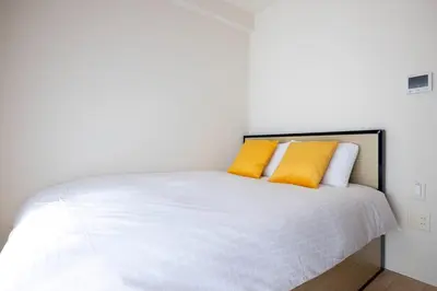 a bedroom with a white bed with two yellow pillows at KiSETSU\u795e\u697d\u5742 in Tokyo