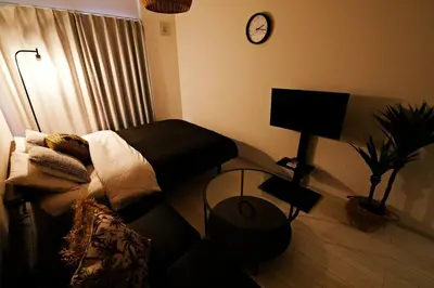 a living room with a couch and a clock on the wall at \u30bb\u30f3\u30c8\u30ec\u30a4 \u62bc\u4e0a\u30ce\u30fc\u30b9103 in Tokyo