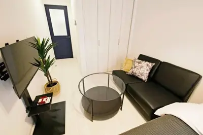 a living room with a black couch and a glass table at \u30bb\u30f3\u30c8\u30ec\u30a4 \u62bc\u4e0a\u30ce\u30fc\u30b9103 in Tokyo