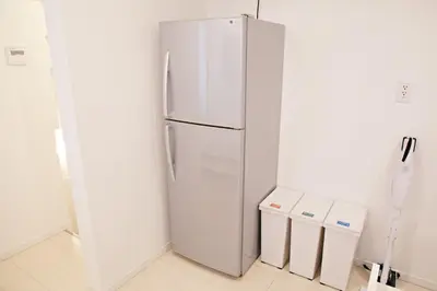 a white refrigerator in a kitchen with two trash cans at \u897f\u5de3\u9d28HOUSE in Tokyo