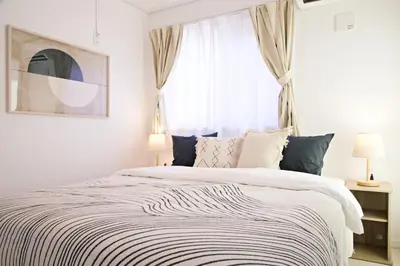 a white bedroom with a large bed and a window at \u897f\u5de3\u9d28HOUSE in Tokyo
