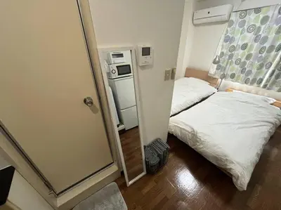 a small room with a bed and a refrigerator at \u5c71\u624b\u7dda\u5de3\u9d28\u99c5\u307e\u3067\u5f92\u6b69\uff15\u5206\u306e\u5feb\u9069\u306a\u30ef\u30f3\u30eb\u30fc\u30e0 in Tokyo