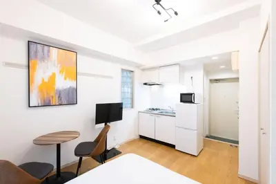 a kitchen with white cabinets and a table and chairs at Ihatov Komazawa in Tokyo
