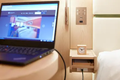 a laptop computer sitting on a table next to a bed at The Royal Park Hotel Ginza 6-Chome in Tokyo