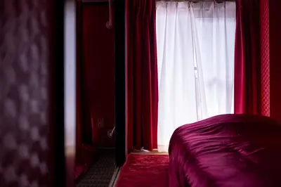 a bedroom with a bed and a window with red curtains at Geisha Expelience Stay in Tokyo