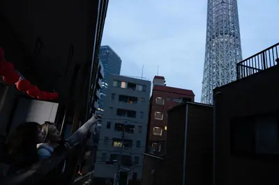a man and woman standing on a balcony in a city at Geisha Expelience Stay in Tokyo