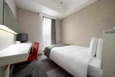 a hotel room with a bed and a desk and a sink at Sotetsu Fresa Inn Shimbashi-Karasumoriguchi in Tokyo
