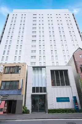 a large white building with windows on a street at Sotetsu Fresa Inn Shimbashi-Karasumoriguchi in Tokyo