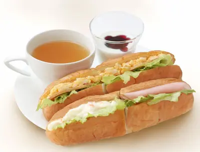 two sandwiches on a plate next to a cup of coffee at Sotetsu Fresa Inn Shimbashi-Karasumoriguchi in Tokyo