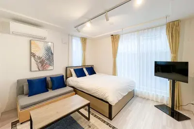a bedroom with a bed and a couch and a television at KiSETSU\u65e9\u7a32\u7530II in Tokyo
