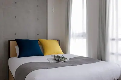 a bedroom with a bed with blue and yellow pillows at KiSETSU\u65e9\u7a32\u7530II in Tokyo