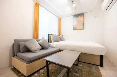 a room with a bed and a couch and a table at KiSETSU\u65e9\u7a32\u7530II in Tokyo