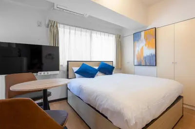 a bedroom with a bed with blue pillows and a table at S-K MANSION in Tokyo