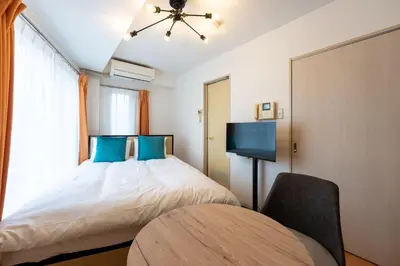 a bedroom with a bed with blue pillows and a chair at S-K MANSION in Tokyo