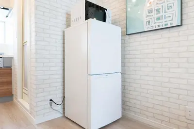 a white refrigerator in a room with a brick wall at Kisa in Tokyo
