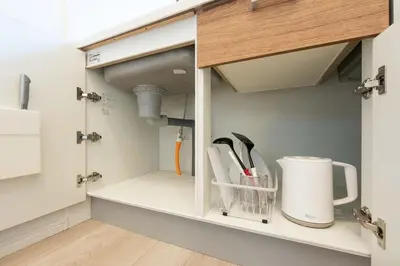 a kitchen cupboard with a sink and utensils at Kisa in Tokyo