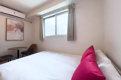 a bedroom with a white bed with a pink pillow at \u30a8\u30ec\u30ac\u30f3\u30c8\u30cf\u30a6\u30b9 in Tokyo