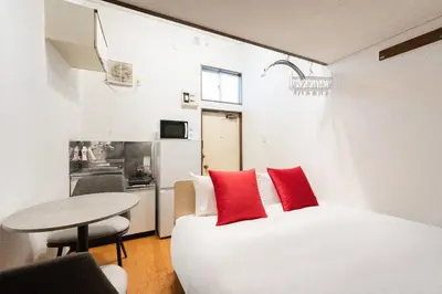 a bedroom with a white bed with red pillows and a table at \u30b0\u30ea\u30fc\u30f3 \u30d2\u30eb in Tokyo