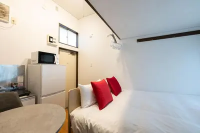 a small room with a bed with red pillows at \u30b0\u30ea\u30fc\u30f3 \u30d2\u30eb in Tokyo